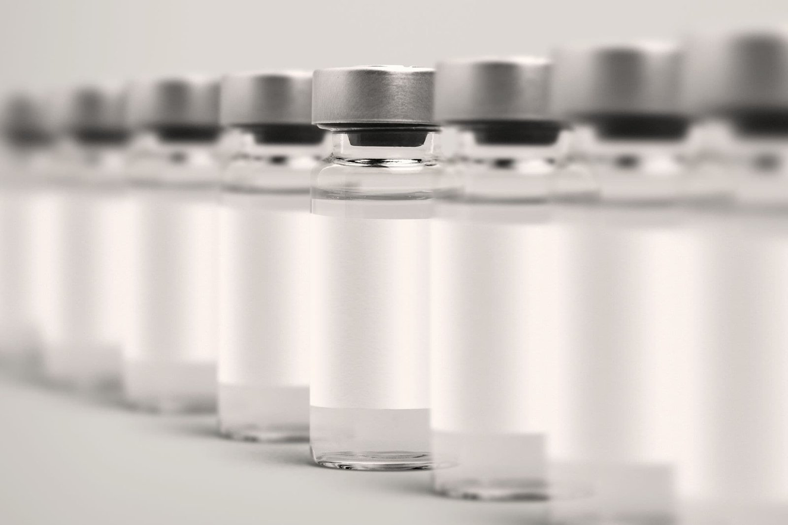 A row of glass vials with blank white labels